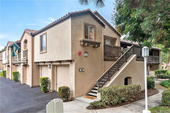Front view of a two-story townhouse with stairs leading to the entrance.