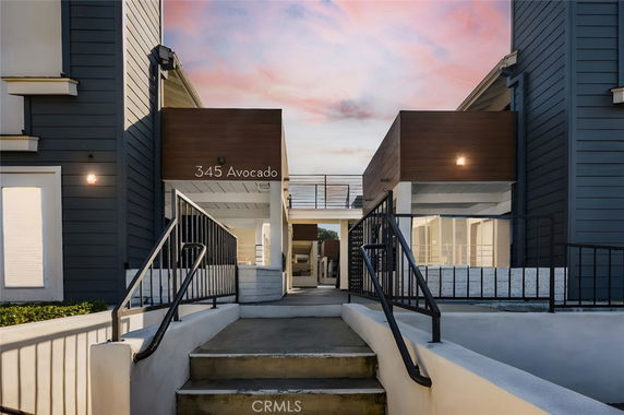 Front view of a modern building entrance with stairs and railings