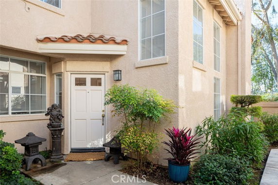 Front view of a two-story house entrance with decorative plants.