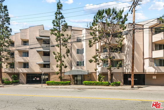 Front view of a multi-story building with balconies and trees.