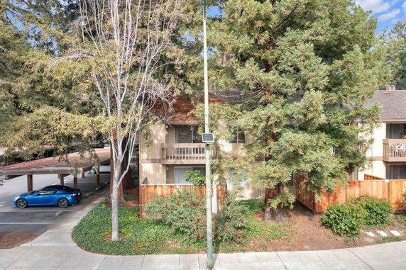 Front view of a two-story apartment building with balconies and adjacent parking area.