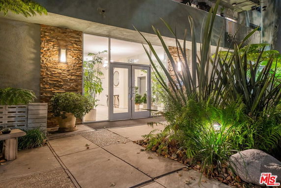 Front view of a modern building entrance with glass doors and landscaping.