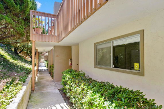 Exterior view of a walkway by a beige building with a balcony.