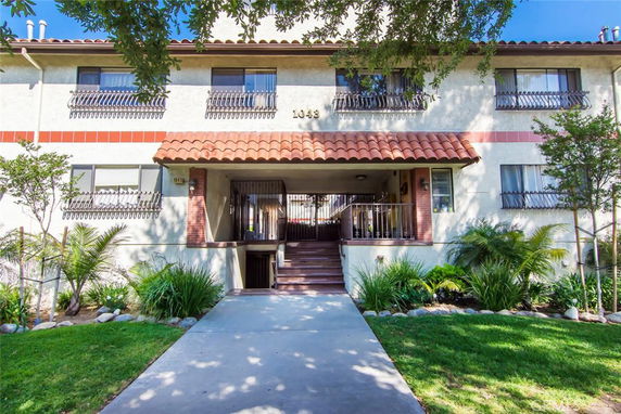 Front view of a multi-story residential building with a tiled roof and entrance.