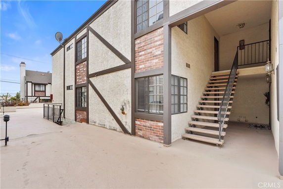 Front view of a two-story building with an exterior staircase and brick accents.