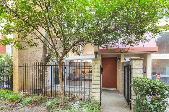 Front view of a building entrance with a metal gate and surrounding trees.