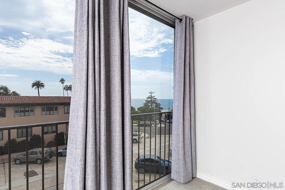 View through a window showing distant ocean and nearby building