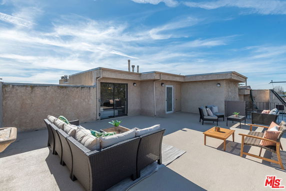 Rooftop with outdoor seating and small building access.