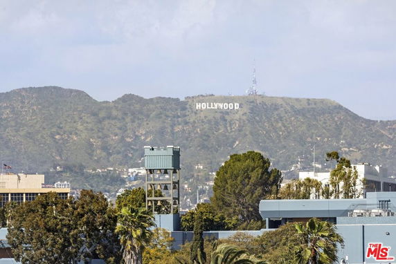 Distant view of a landmark sign on hills with surrounding buildings and trees.