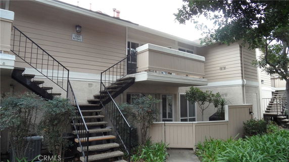Front view of a two-story residential building with external staircases and balconies.