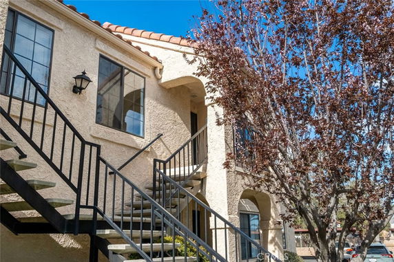 Front view of a two-story building with exterior stairs and arched windows.