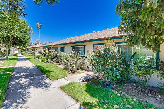 Front view of a single-story house with a garden path and green lawn.