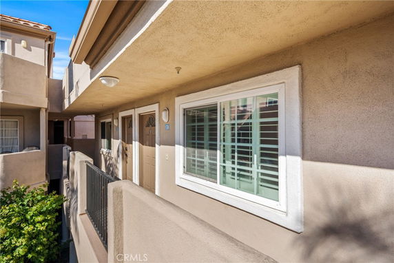 Exterior view of an apartment building with two doors and a window along a corridor.