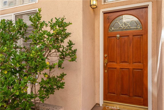 Front view of a house entrance with a wooden door and decorative glass panel.