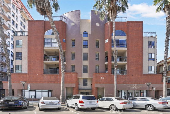 Front view of a multi-story building with balconies and a parking area.