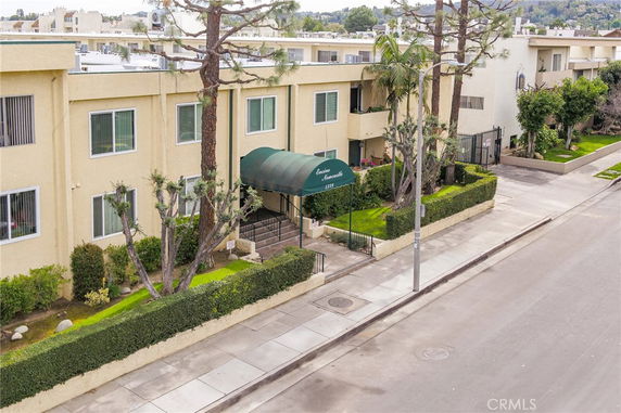 Front view of a multi-story residential building with a green entrance canopy.