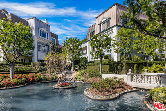 Front view of a multi-story building with landscaped garden and water feature.
