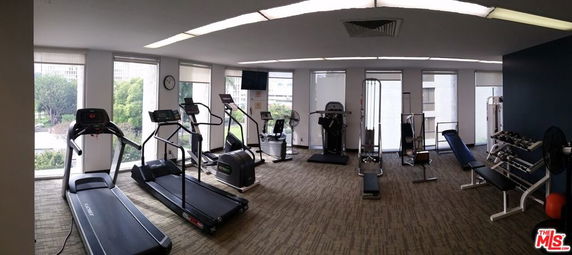 Indoor gym area with exercise equipment and large windows.