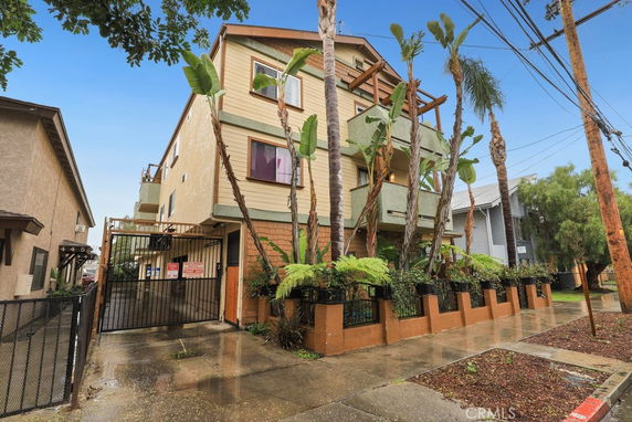Front view of a multi-story apartment building with balconies and plants.