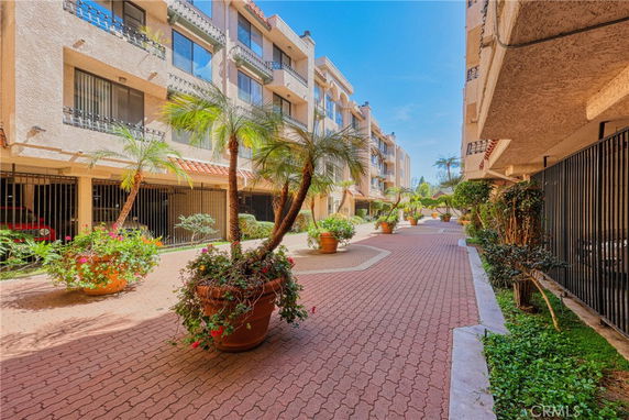 Front view of an apartment building with balconies and potted plants.