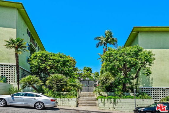 Front view of a two-story apartment building with green exterior and landscaped entrance.
