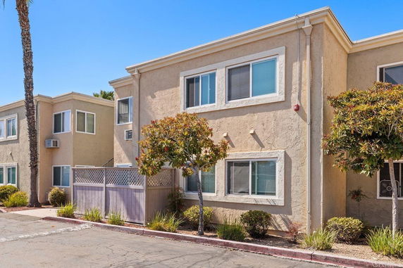 Front view of a two-story apartment building with beige stucco walls and white-framed windows.