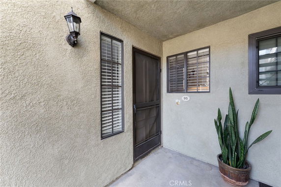 Front view of a house entrance with windows and a potted plant.