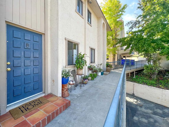 Front view of a two-story building with a blue door and a concrete path leading to it.