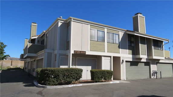 Front view of a two-story building with garages and a balcony.