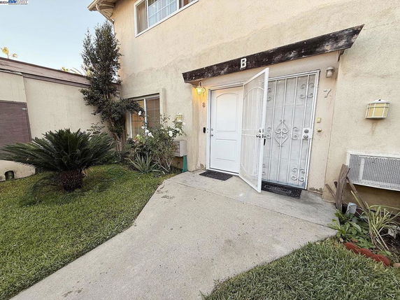 Front view of a two-story house with a white door and small garden area.
