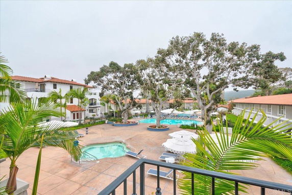 View of an outdoor area with swimming pools surrounded by buildings with red-tiled roofs.