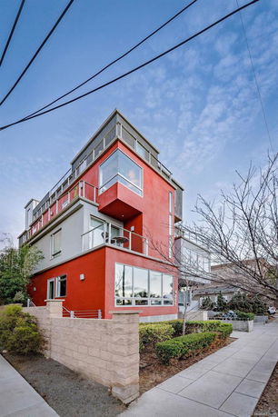 Front view of a modern multi-story building with a vibrant red exterior and large windows.