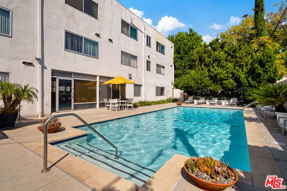 Swimming pool adjacent to a building with several floors and outdoor seating.