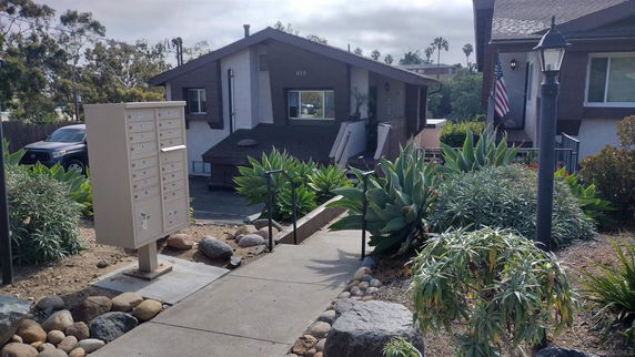 Front view of a single-story house with a sloped roof and surrounding landscaping.