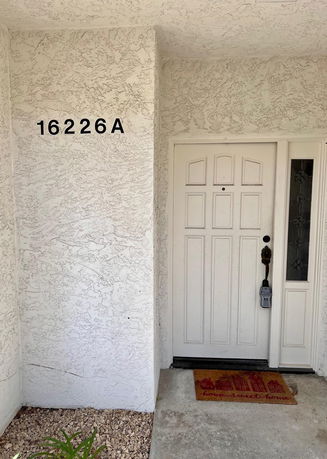 Front view of a house entrance with a white door and address number.