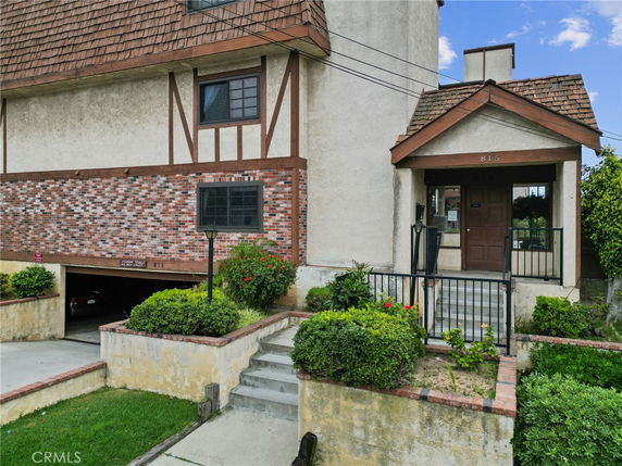 Front view of a multi-story building with brick and stucco facade and a covered entrance.