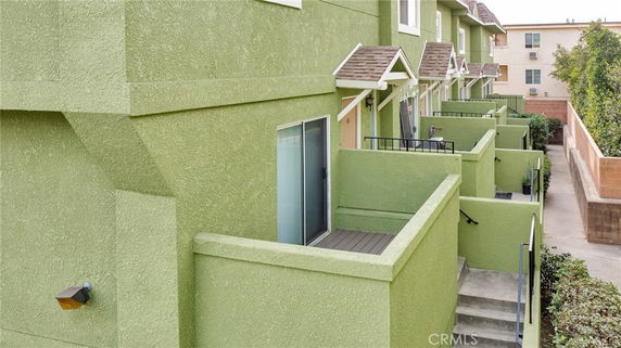 Side view of a green multi-level residential building with small balconies.
