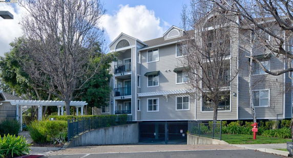 Front view of a multi-story residential building with balconies and a gabled roof.