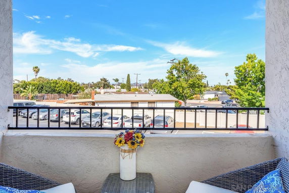 View from a balcony showing parked cars and trees in the surrounding area.
