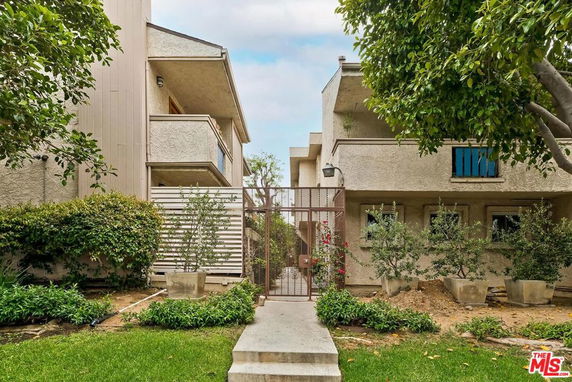 Front view of a multi-story residential building with balconies and a gated entrance.