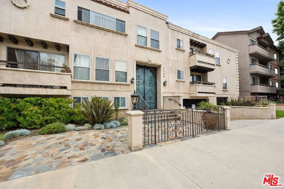 Front view of a multi-story apartment building with balconies and a decorative entrance.