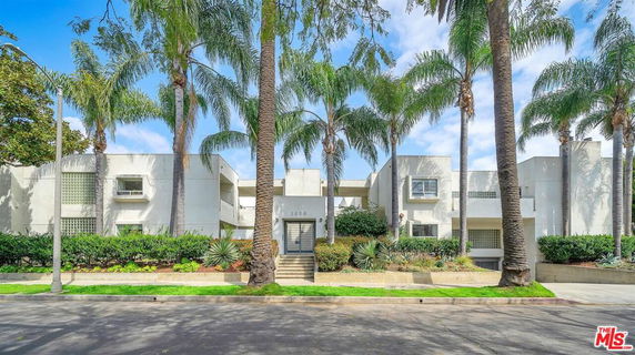 Front view of a modern multi-story residential building with palm trees.
