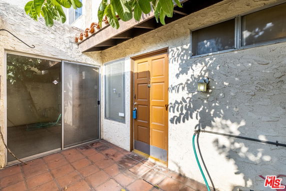 Front view of a house with a wooden door and sliding glass patio doors.