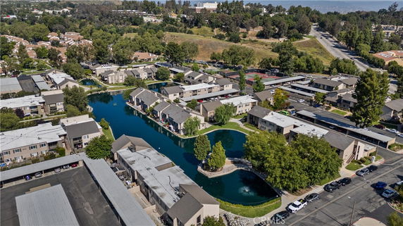 Aerial view of a residential complex with multiple buildings, surrounded by greenery and water bodies.