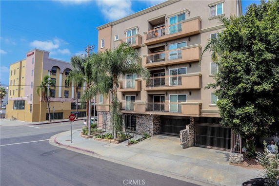 Front view of a multi-story residential building with balconies and a gated entrance.