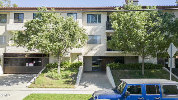 Front view of a multi-story residential building with balconies and a garage entrance.