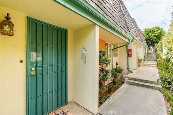 Front view of a building with a green door and decorative elements, along a pathway.