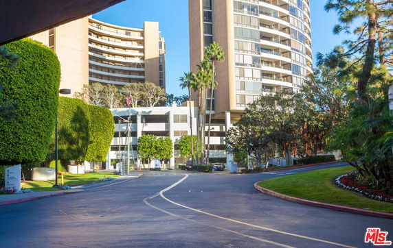 Front view of a high-rise building with circular balconies and surrounding landscaping.