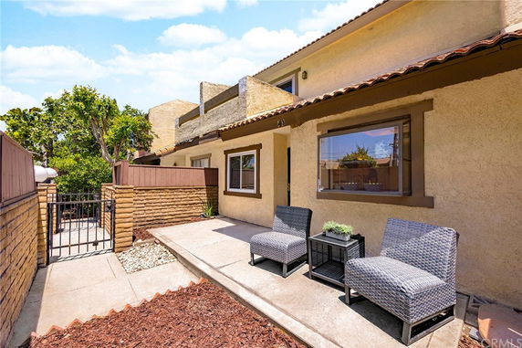 Front view of a house with outdoor seating and a gate entrance.