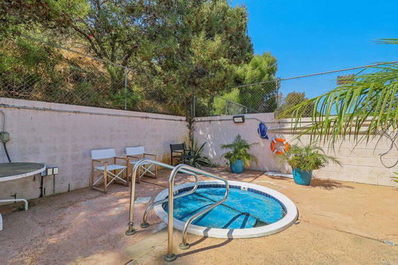 Outdoor area with a small circular pool, surrounded by chairs and potted plants.